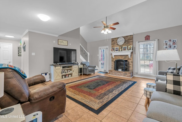 tiled living room featuring a brick fireplace, ornamental molding, and ceiling fan