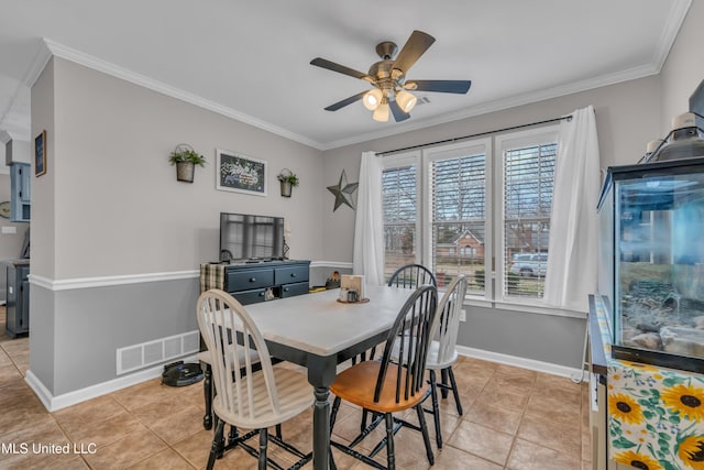 tiled dining area with ceiling fan and crown molding