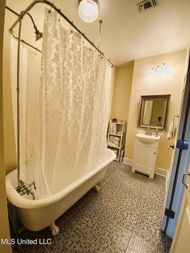 full bathroom with tile patterned flooring, vanity, visible vents, a freestanding bath, and baseboards