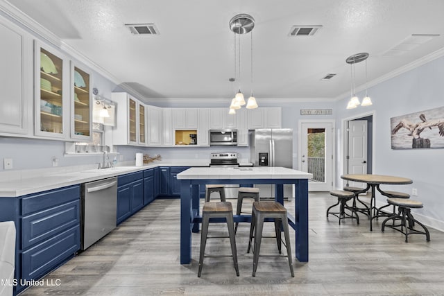 kitchen with visible vents, appliances with stainless steel finishes, ornamental molding, blue cabinets, and a sink