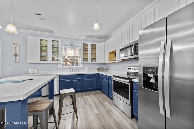 kitchen with blue cabinetry, visible vents, appliances with stainless steel finishes, white cabinets, and light wood-type flooring