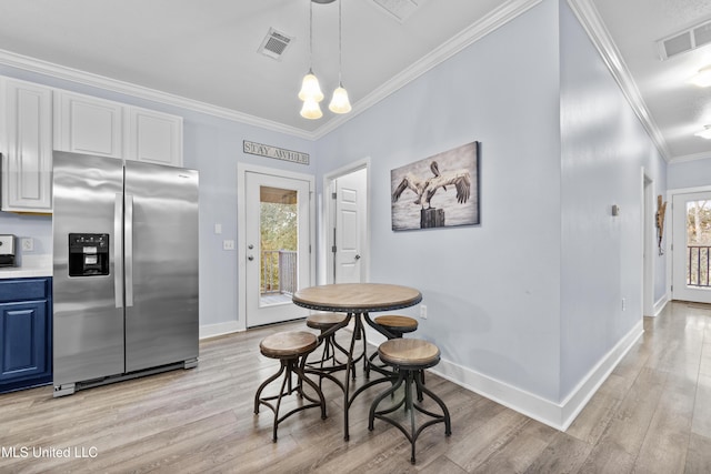 dining room featuring ornamental molding, visible vents, and light wood-style floors