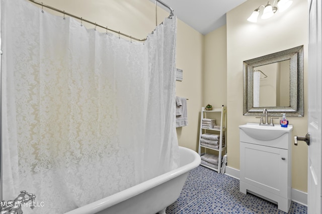 full bathroom with a soaking tub, vanity, and baseboards