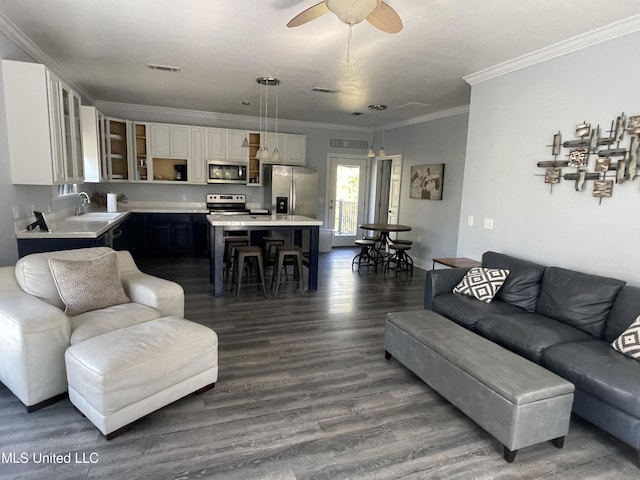 living room featuring ceiling fan, ornamental molding, dark wood-style flooring, and visible vents