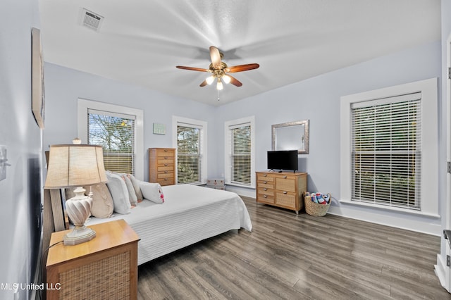 bedroom with a ceiling fan, visible vents, and wood finished floors