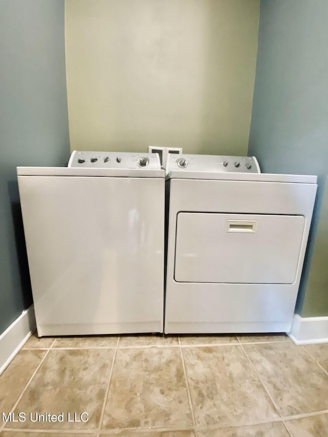 laundry area featuring laundry area, baseboards, washer and clothes dryer, and light tile patterned flooring