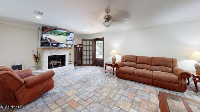 living room featuring ceiling fan, ornamental molding, and a brick fireplace