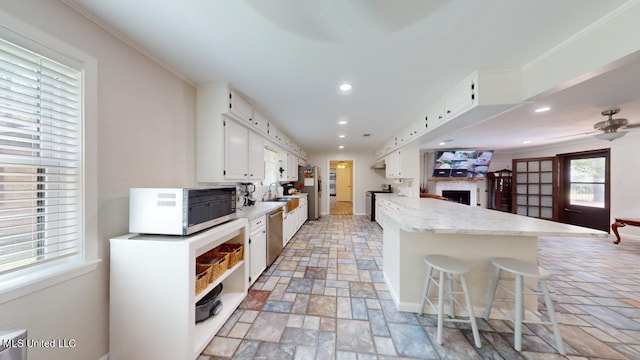 kitchen with sink, white cabinetry, stainless steel appliances, ornamental molding, and a breakfast bar