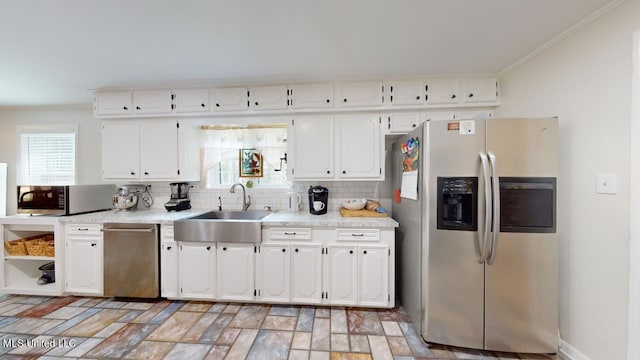 kitchen with appliances with stainless steel finishes, crown molding, white cabinetry, and sink