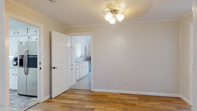 spare room featuring crown molding, light wood-type flooring, and ceiling fan