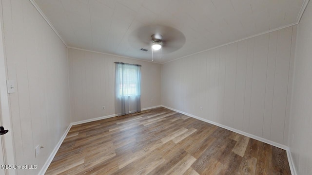 empty room featuring wood walls, crown molding, hardwood / wood-style flooring, and ceiling fan