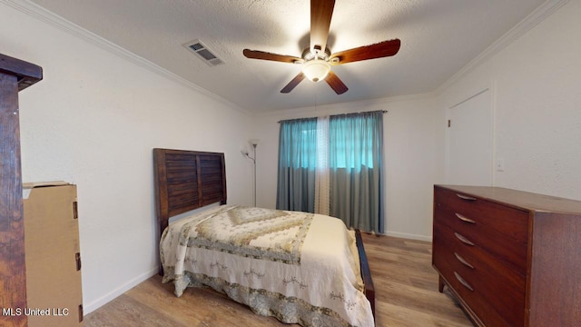 bedroom featuring ceiling fan, ornamental molding, a textured ceiling, and light wood-type flooring