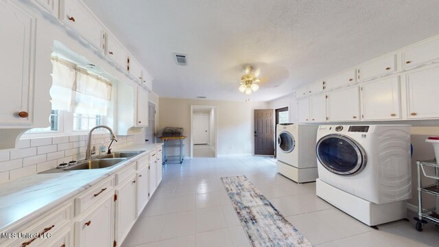 laundry room featuring washer and clothes dryer, sink, light tile patterned floors, cabinets, and ceiling fan