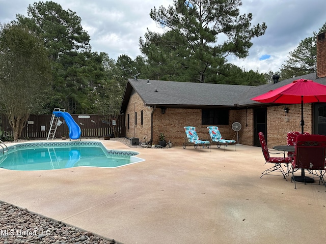 view of swimming pool featuring a water slide and a patio