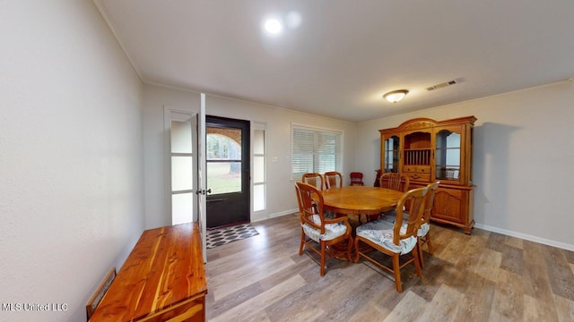 dining room with ornamental molding and light hardwood / wood-style flooring