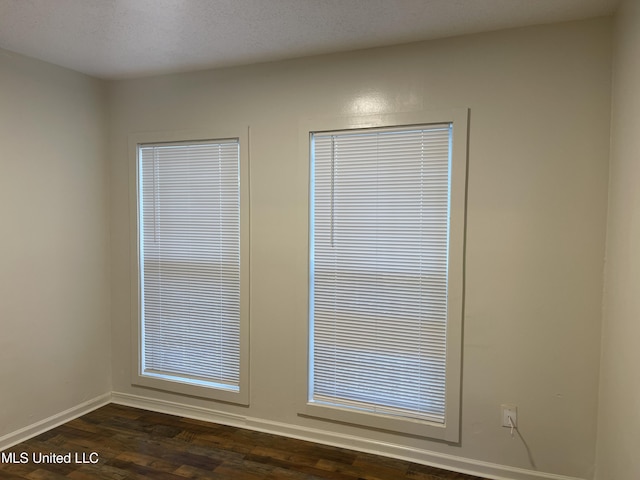 room details featuring wood finished floors, baseboards, and a textured ceiling