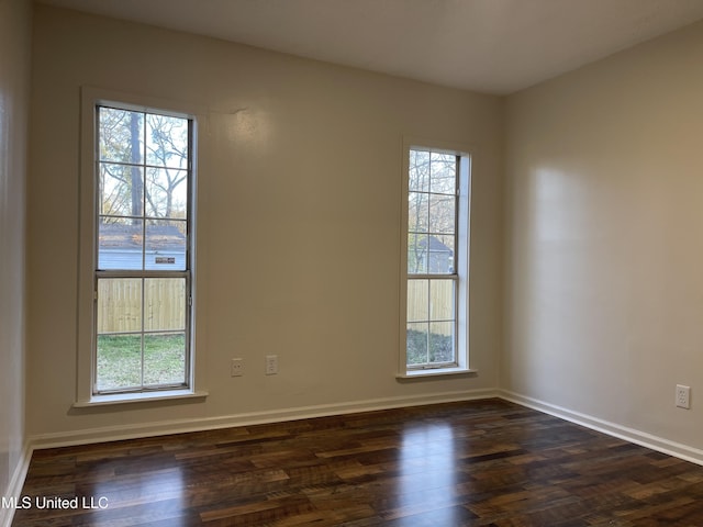 unfurnished room with baseboards, plenty of natural light, and dark wood-type flooring