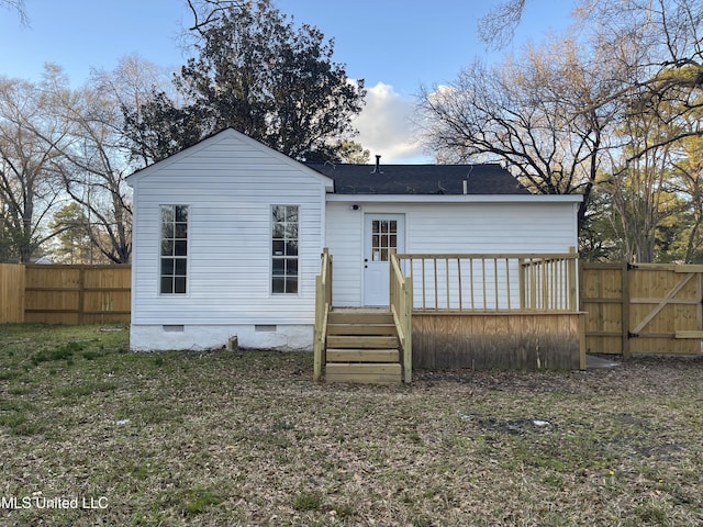 back of property with crawl space, a wooden deck, and fence