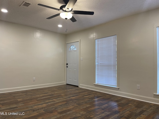 entrance foyer with baseboards, visible vents, dark wood-style flooring, and a textured ceiling