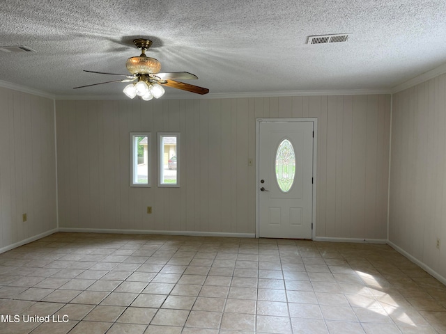 entrance foyer featuring wooden walls, a textured ceiling, light tile patterned floors, and plenty of natural light