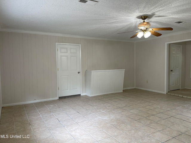 empty room featuring wooden walls, crown molding, a textured ceiling, and ceiling fan