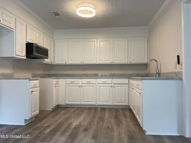 kitchen with dark wood-type flooring, a textured ceiling, ornamental molding, and white cabinets