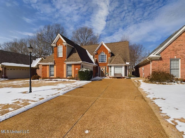 view of front of property featuring brick siding, driveway, and roof with shingles