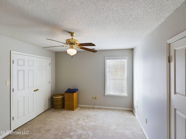 unfurnished bedroom featuring a ceiling fan, carpet, a textured ceiling, and baseboards