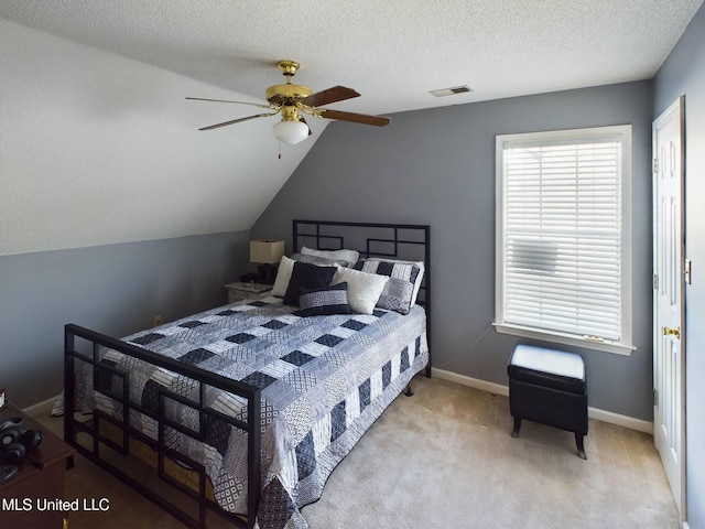 carpeted bedroom featuring visible vents, a ceiling fan, vaulted ceiling, a textured ceiling, and baseboards