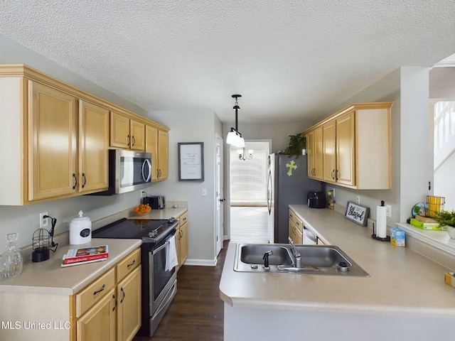 kitchen featuring dark wood-style floors, a peninsula, stainless steel appliances, light countertops, and a sink