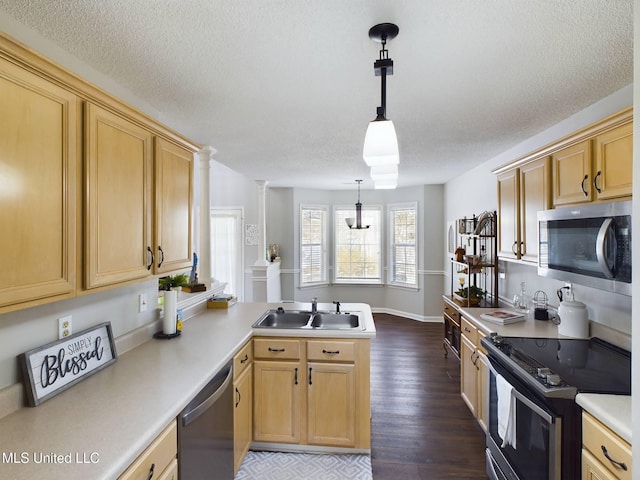 kitchen featuring dark wood-type flooring, a peninsula, stainless steel appliances, light countertops, and a sink