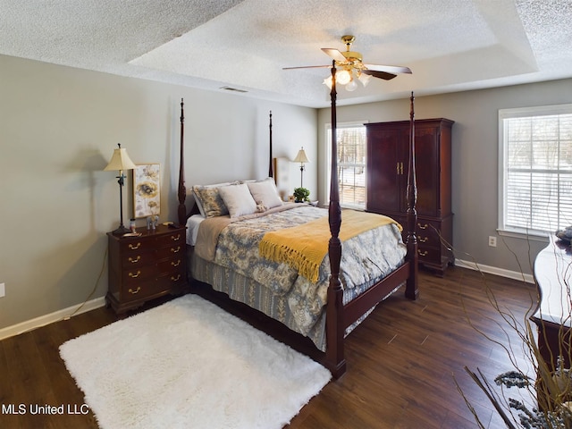 bedroom with visible vents, dark wood finished floors, a textured ceiling, and baseboards