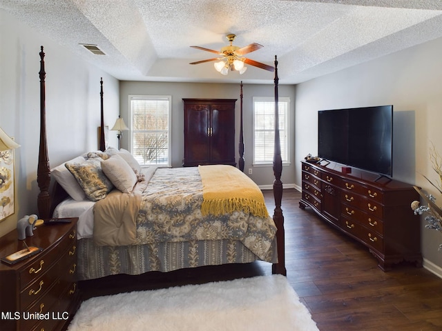 bedroom featuring ceiling fan, multiple windows, visible vents, and dark wood finished floors