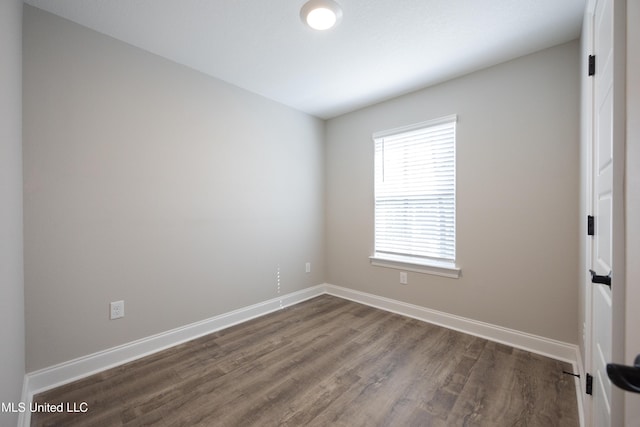 spare room featuring dark wood-type flooring and baseboards