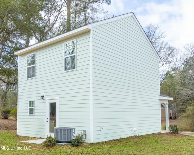 view of side of property with cooling unit and a lawn