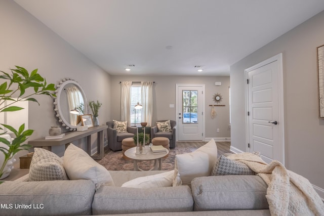 living room with recessed lighting, visible vents, baseboards, and wood finished floors