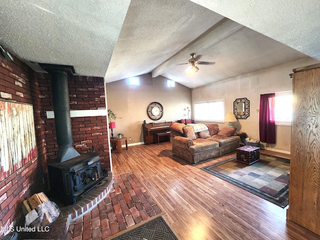 living room featuring a wood stove, a wealth of natural light, a textured ceiling, and vaulted ceiling with beams