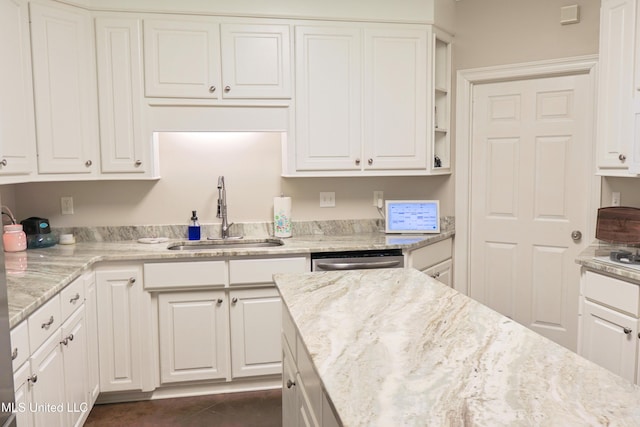 kitchen featuring light stone counters, stainless steel dishwasher, sink, and white cabinets