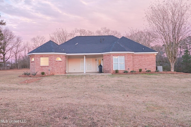 back house at dusk featuring a yard and a patio area