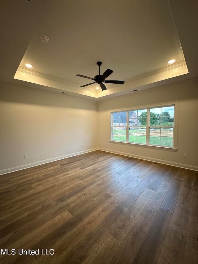 empty room with a raised ceiling, ceiling fan, crown molding, and dark hardwood / wood-style floors