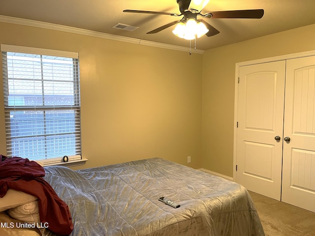 carpeted bedroom featuring ornamental molding, a closet, and ceiling fan