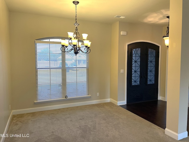 foyer entrance with an inviting chandelier, french doors, and carpet flooring