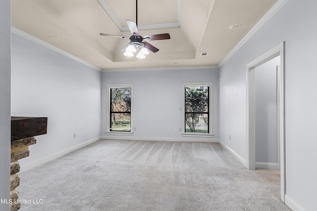 unfurnished living room featuring plenty of natural light, a ceiling fan, a tray ceiling, and carpet floors