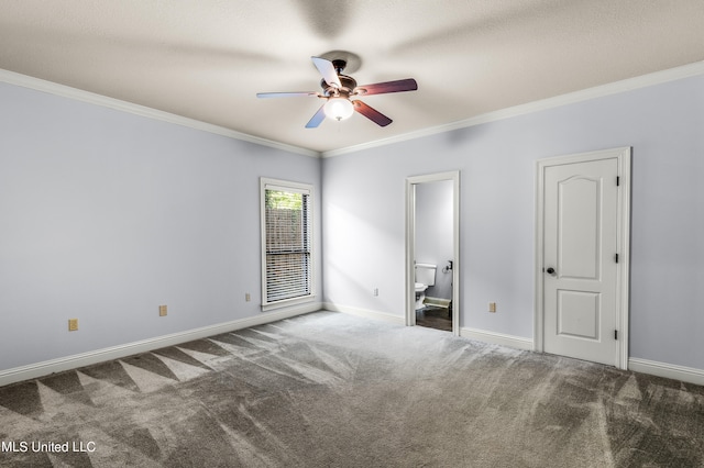 unfurnished bedroom with crown molding, dark colored carpet, ensuite bathroom, and ceiling fan