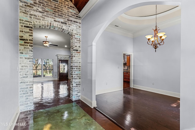 interior space featuring a raised ceiling, ornamental molding, dark hardwood / wood-style flooring, and ceiling fan with notable chandelier