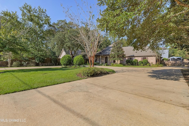 view of front of house with brick siding, driveway, fence, and a front yard