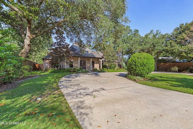 obstructed view of property featuring fence, driveway, and a front yard