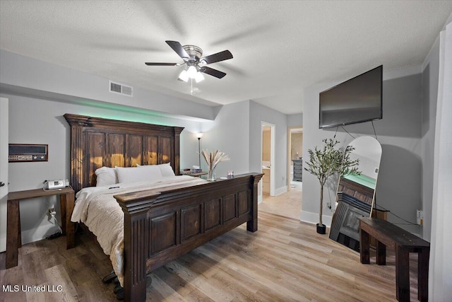 bedroom with light hardwood / wood-style floors, a textured ceiling, and ceiling fan