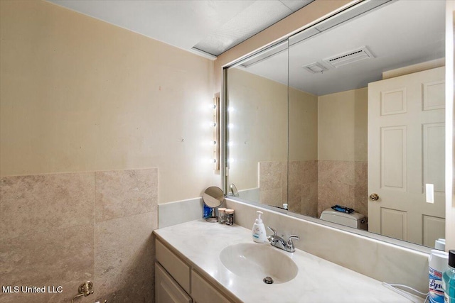 bathroom with vanity, toilet, and tile walls