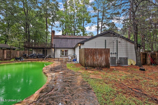 rear view of house featuring cooling unit and a fenced in pool